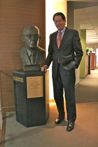 Craig Higgs stands next to bust of his father and founding partner, Dewitt ‘Dutch’ Higgs.