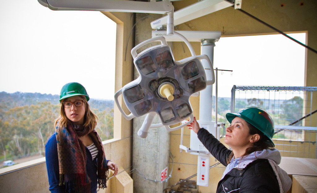 Two structural engineering graduate students examine surgery lights set up in a five-story building that was tested on the shake table at the Englekirk Center in April 2013.