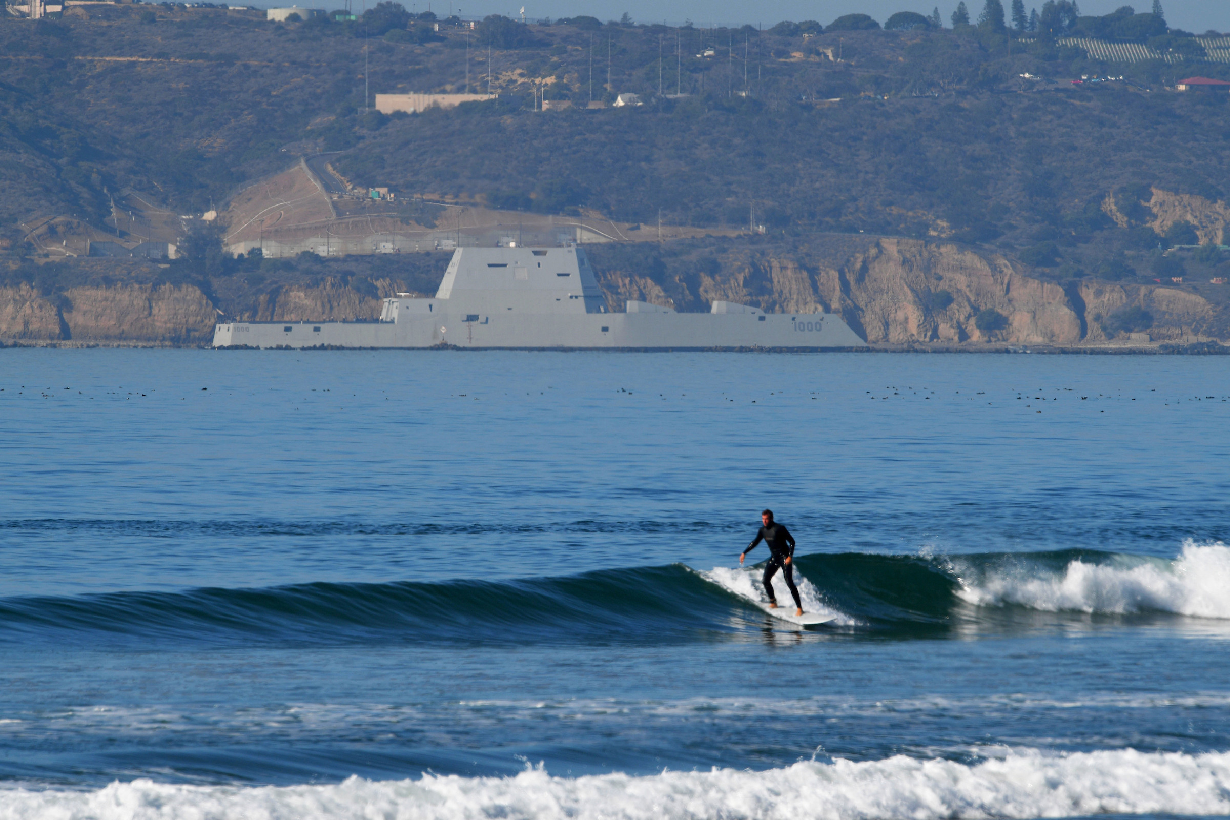 A surfer appears unaware as the USS Zumwalt transits the San Diego channel on its way to her new homeport at Naval Base San Diego on Thursday. (U.S. Navy photo by Petty Officer 2nd Class Timothy M. Black)