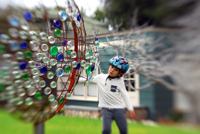 Scripps scientist Sasha Gershunov’s son Anton spins artist Oscar Romo’s mixed media sculpture, ‘Atmospheric Rivers.’ The art installation is made of recycled and repurposed materials, including sawn-off pieces of glass bottles and bicycle sprockets foraged from the Tijuana River. (Photo: Sasha Gershunov)
