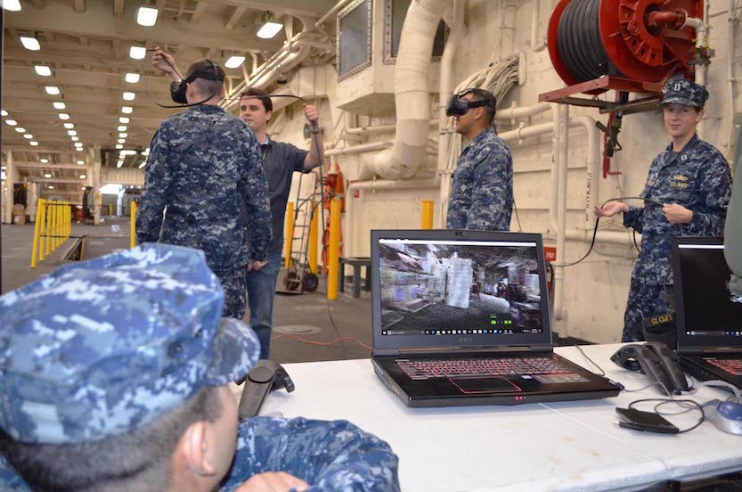 SPAWAR military and civilian employees assist sailors during a virtual reality demonstration on board the amphibious transport dock ship USS Anchorage. The week prior, three-dimensional images were produced during a ship scan event of various shipboard spaces on Anchorage. (U.S. Navy photo by Dawn Stankus)