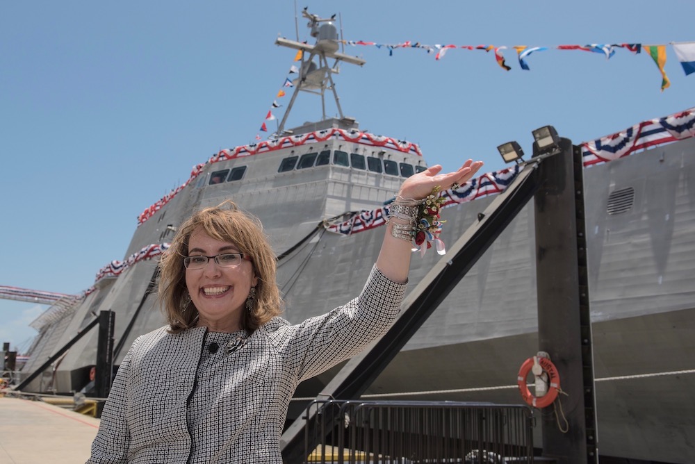 Former U.S. Representative Gabrielle Giffords waves to a crowd in front of the littoral combat ship USS Gabrielle Giffords, named for her. Giffords was on the stage as Dr. Jill Biden christened the ship at Austal USA in Mobile, Ala. (Photo courtesy Austal USA)