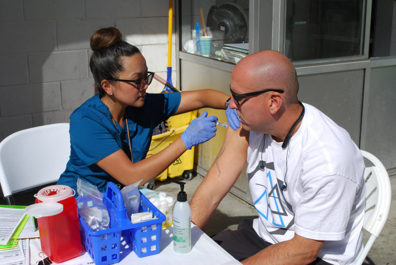 County nurse Jeanina Rumbaoa vaccinates a patient outside a public restroom.
