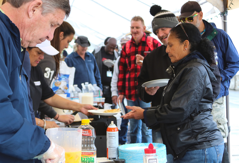 Volunteers serve food to some of the homeless at one of three bridge shelters opened in San Diego. (Photo by Brennan Scott)