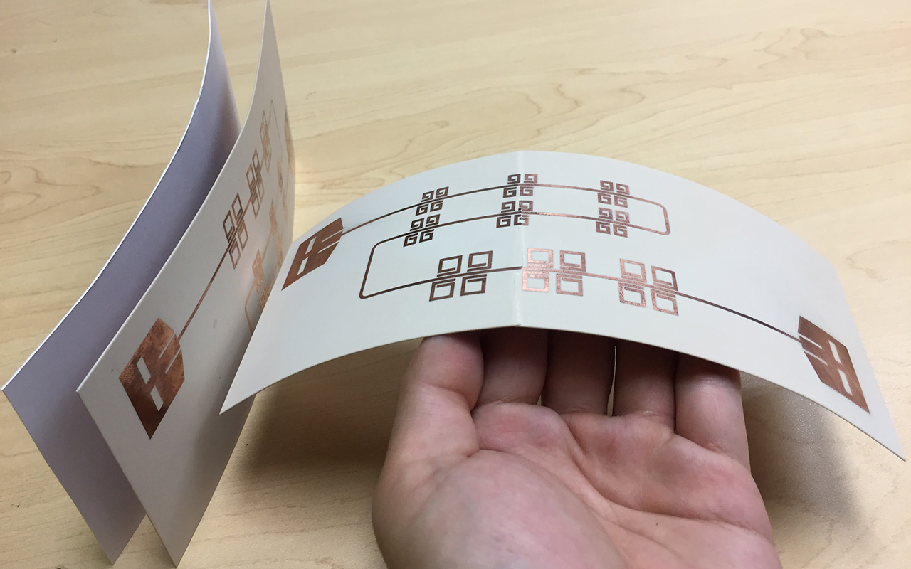 Printed thin, flexible LiveTag tags in comparison with a piece of photo paper (far left). (Photo courtesy of Xinyu Zhang)