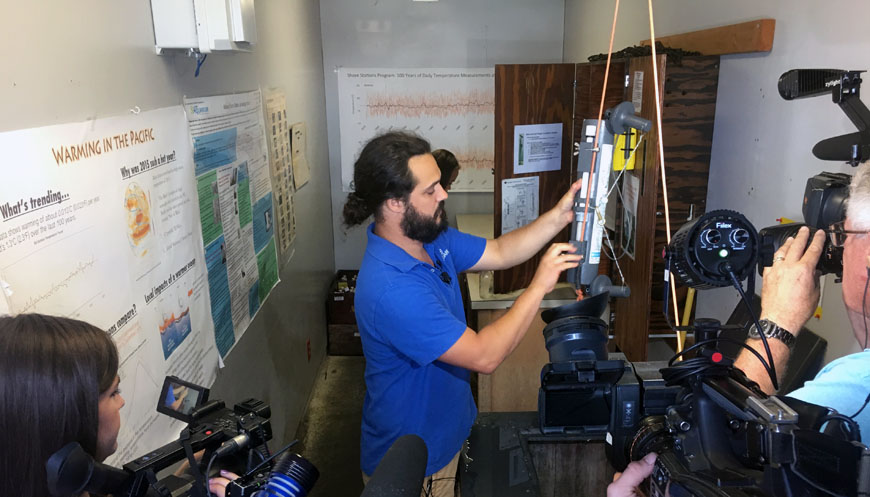 News media members film seawater temperature measurements at Scripps Pier, Aug. 2, 2018. (Photo courtesy of Scripps Institution of Oceanography)