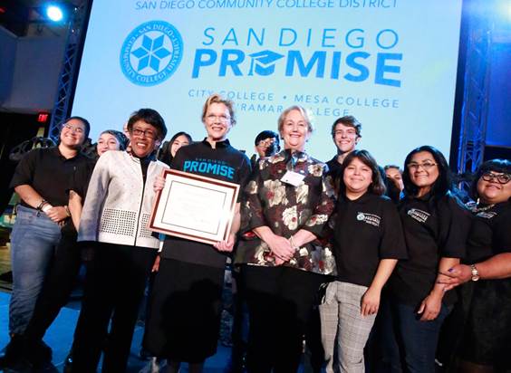 SDCCD Chancellor Constance Carroll presents Annette Bening with a plaque recognizing the establishment of the Annette Bening Promise Scholarship as San Diego Mesa College President Pamela Luster and San Diego Promise students look on. 