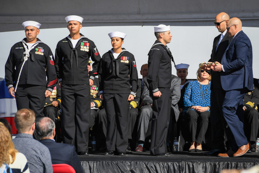  James and Joseph Monsoor, brothers to Michael Monsoor, pass the long glass to the first watch during the commissioning ceremony for the guided-missile destroyer USS Michael Monsoor. (U.S. Navy photo by Mass Communication Specialist 2nd Class Alex Millar.) 