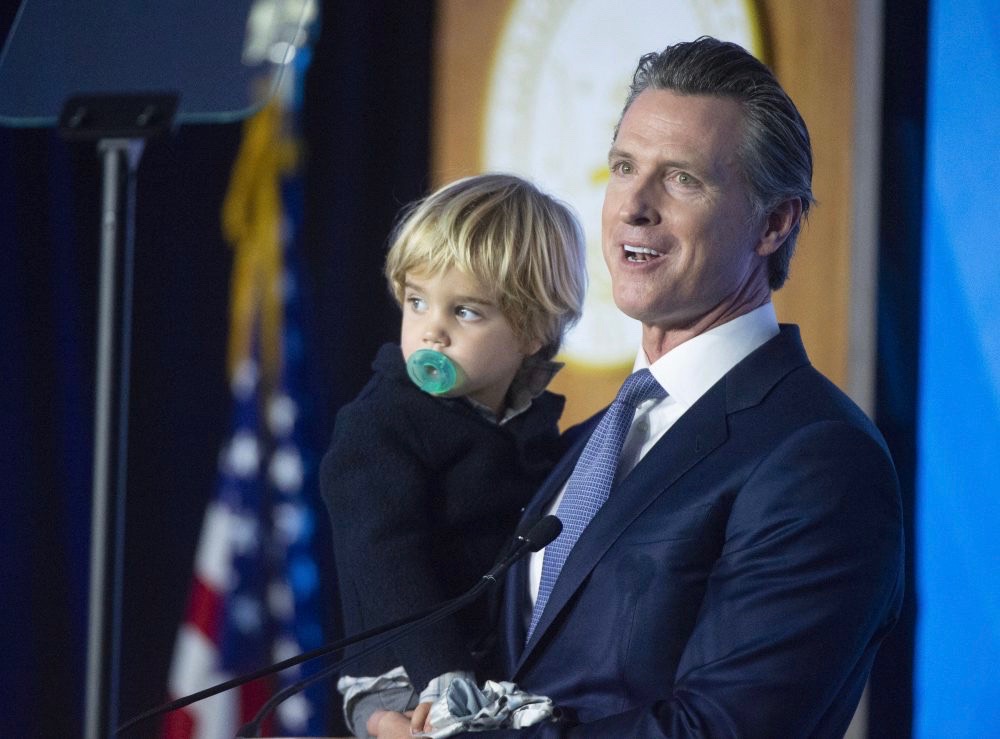 Gavin Newsom holds his son Dutch, 2, after he was sworn in as the 40th Governor of California. (Photo for CALmatters by Randy Pench)