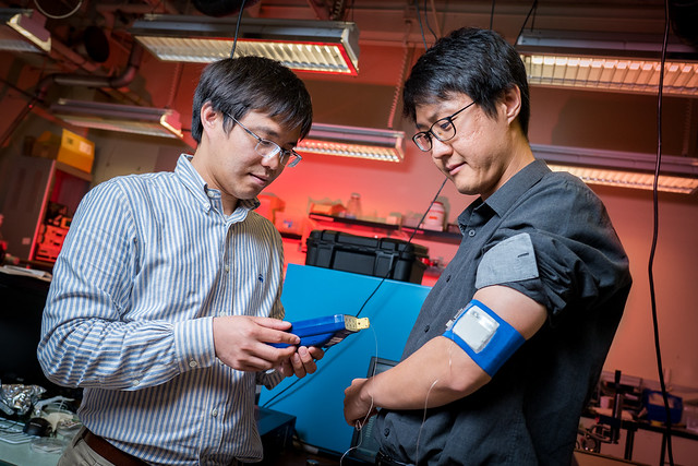 Renkun Chen (left), UC San Diego professor of mechanical and aerospace engineering, measures the temperature of the prototype cooling/heating system worn by Sahngki Hong (right), the study's first author. (Photos by David Baillot/UC San Diego Jacobs School of Engineering)