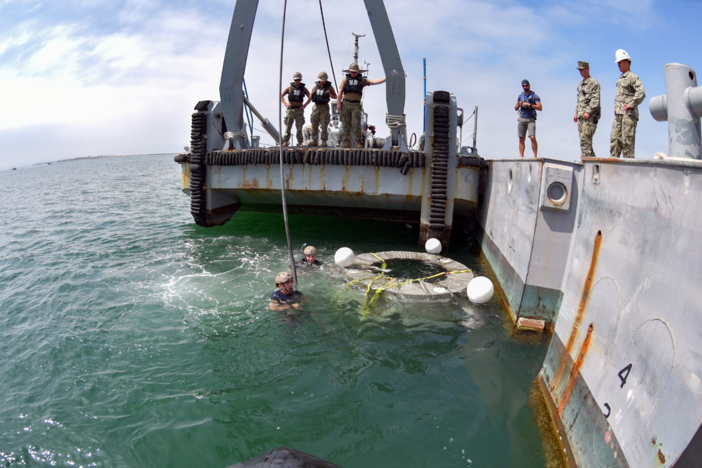 Navy Divers from Explosive Ordnance Disposal Mobile Unit 3 connect the wench line to an amphibious craft in order to lift NASA’s forward bay cover from the water as a part of the Orion Space Shuttle recovery training exercise. This was an experimental exercise for the future launch of the Orion Space Shuttle with training focused on the recovery of the forward bay cover, which is the top of the capsule that detaches after reentering the atmosphere allowing the parachute to deploy for the capsule and the crew inside. (U.S. Navy photo by Mass Communication Specialist 2nd Class Brianna Jones) 