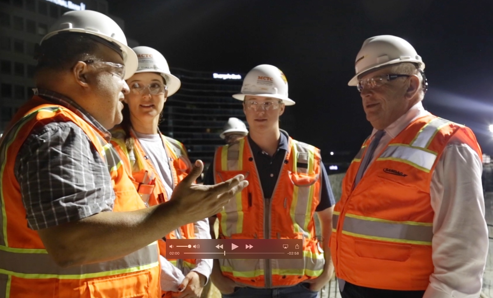 SANDAG Executive Director Hasan Ikhrata, right, speaks with the agency’s construction crew at the site of a concrete pour for the Mid-Coast Trolley Project at Genesee Avenue and La Jolla Village Drive. The pour formed the deck for the elevated Trolley bridge. (Scene from a SANDAG video)