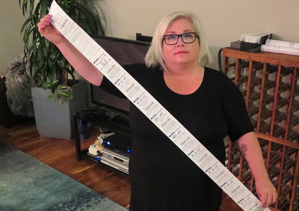 Carol Dahmen poses with a receipt that's more than 4 feet long—for the purchase of a single item. (Photo via Kevin Eckery for CALmatters)