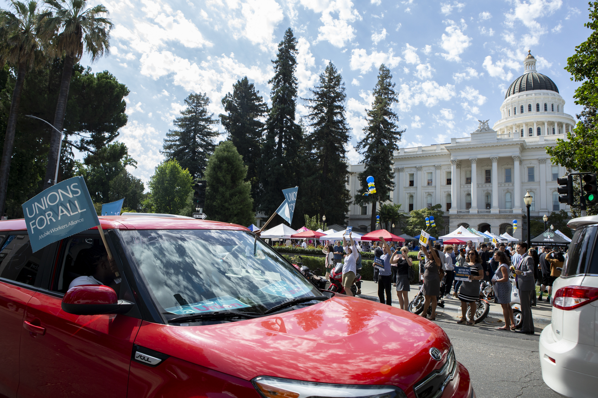 A caravan of Uber and Left drivers passes by the capitol Sacramento while honking and waving flags before a rally in support of AB 5.