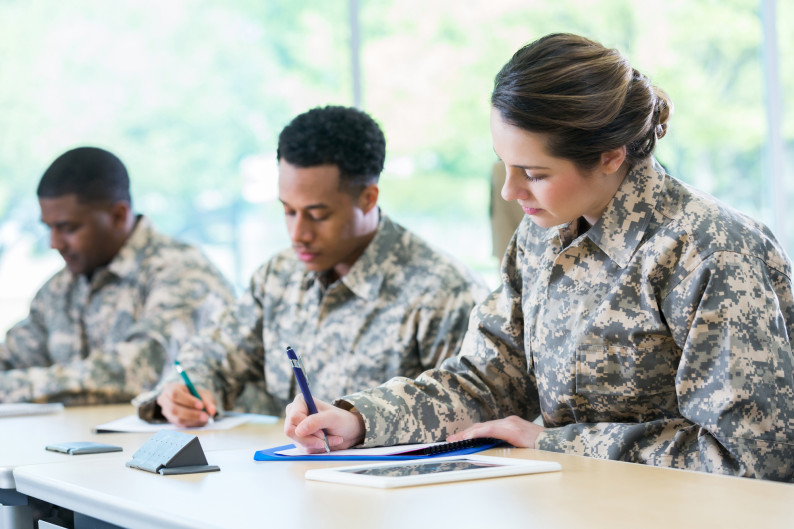 Male and female military cadets take test or take notes during a class at a military academy.