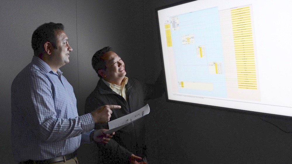 Rajan Kapadia, left, of NAVWAR, works with colleague Khoa Dang to review a draft digital model representing a set of information warfare capabilities for future installation on the aircraft carrier USS Abraham Lincoln. (U.S. Navy photo by Rick Naystatt)