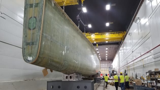 Workers move the composite hull of Sea Hunter II at a facility in Gulfport, Mississippi. (Photo credit: Leidos)