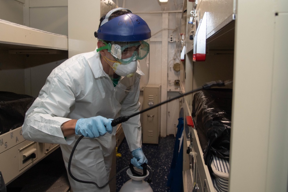 Navy Aviation Electricians Mate 3rd Class Kyle Hernandez disinfects a berthing aboard the San Diego-based aircraft carrier USS Theodore Roosevelt with a multi-surface sanitizer April 12, 2020. The carrier is in Guam. (U.S. Navy photo by Mass Communication Specialist Seaman Kaylianna Genier)