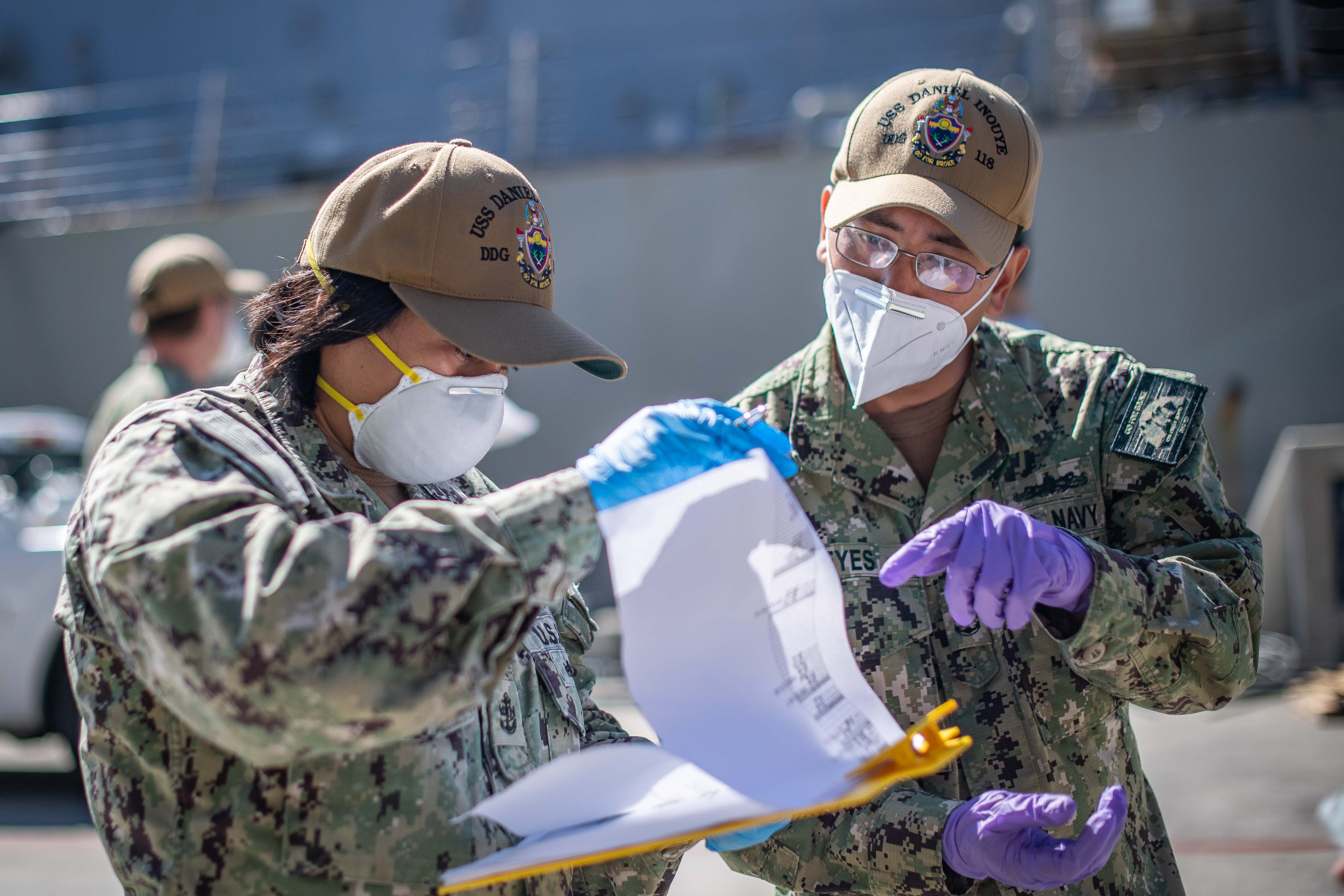 Chief Cryptologic Technician Marisol Swenney, left, and Chief Fire Controlman Roland Reyes, both assigned to the future guided-missile destroyer USS Daniel Inouye, review a muster sheet during crew swap, the next phase of recovery for USS Kidd. The Navy re-tested the crew for COVID-19 and transferred nearly 90 confirmed healthy sailors from quarantine to the ship to replace the caretaker crew that has been aboard since the ship arrived in San Diego on April 28. The new caretaker crew will continue the strategic deep-cleaning regimen and provide essential services for the ship. (U.S. Navy photo by Mass Communication Specialist 2nd Class Alex Corona)