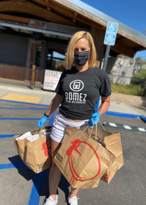 A Gomez Trial Attorneys employee holds meals purchased from The Crack Shack that will go to essential workers in San Diego.