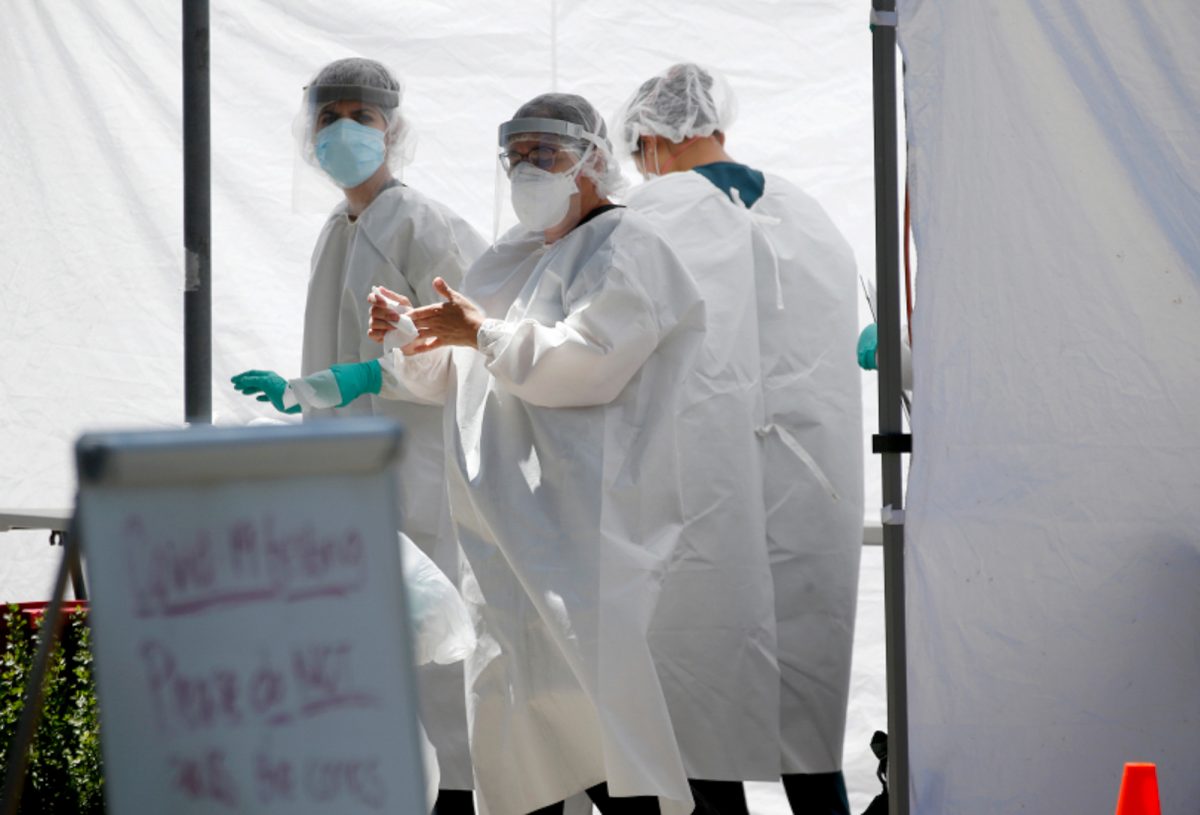 A Clinica de la Raza staff member sanitizes her hands after administering Covid-19 tests in a parking lot in Oakland on July 7. (Photo by Jane Tyska, Bay Area News Group)