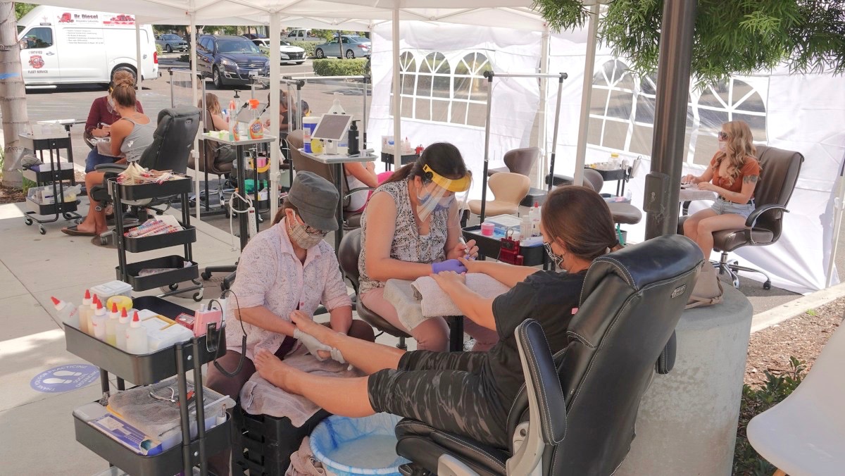 In order to comply with local regulations, a Vista, Ca nail salon operates outside on Aug. 1, 2020. (Photo by Simone Hogan via iStock)