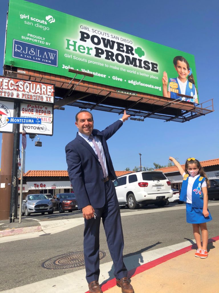 Ronson Shamoun, RJS Law principal and CEO, and Girl Scout Sloane Viora showcase the Girl Scout billboard she is featured in.