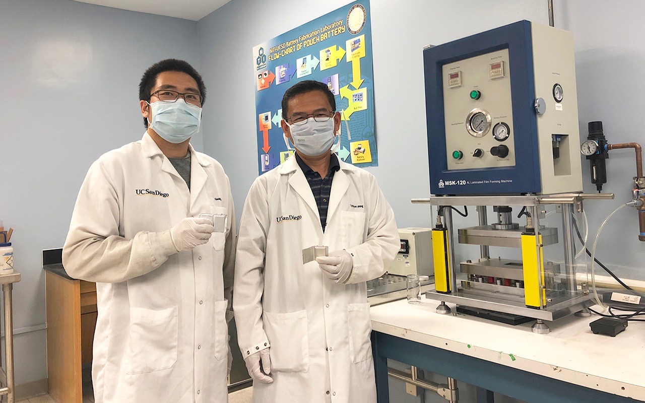 Researchers Haodong Liu and Ping Liu hold batteries made with the disordered rocksalt anode material they discovered, standing in front of a device used to fabricate battery pouch cells. (Photo credit: UC San Diego)