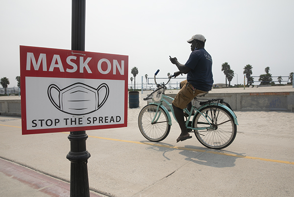 A man bikes along Mission Beach in San Diego on Sept. 9, 2020. (Photo by Anne Wernikoff for CalMatters)