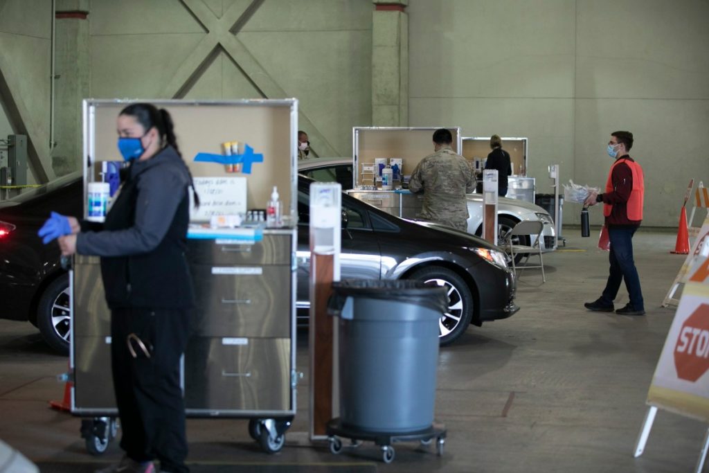 National Guard members and medical personnel administer COVID vaccines to health care workers at a drive-through distribution site at Cal Expo in Sacramento on Jan. 21, 2021. (Photo by Anne Wernikoff, CalMatters)